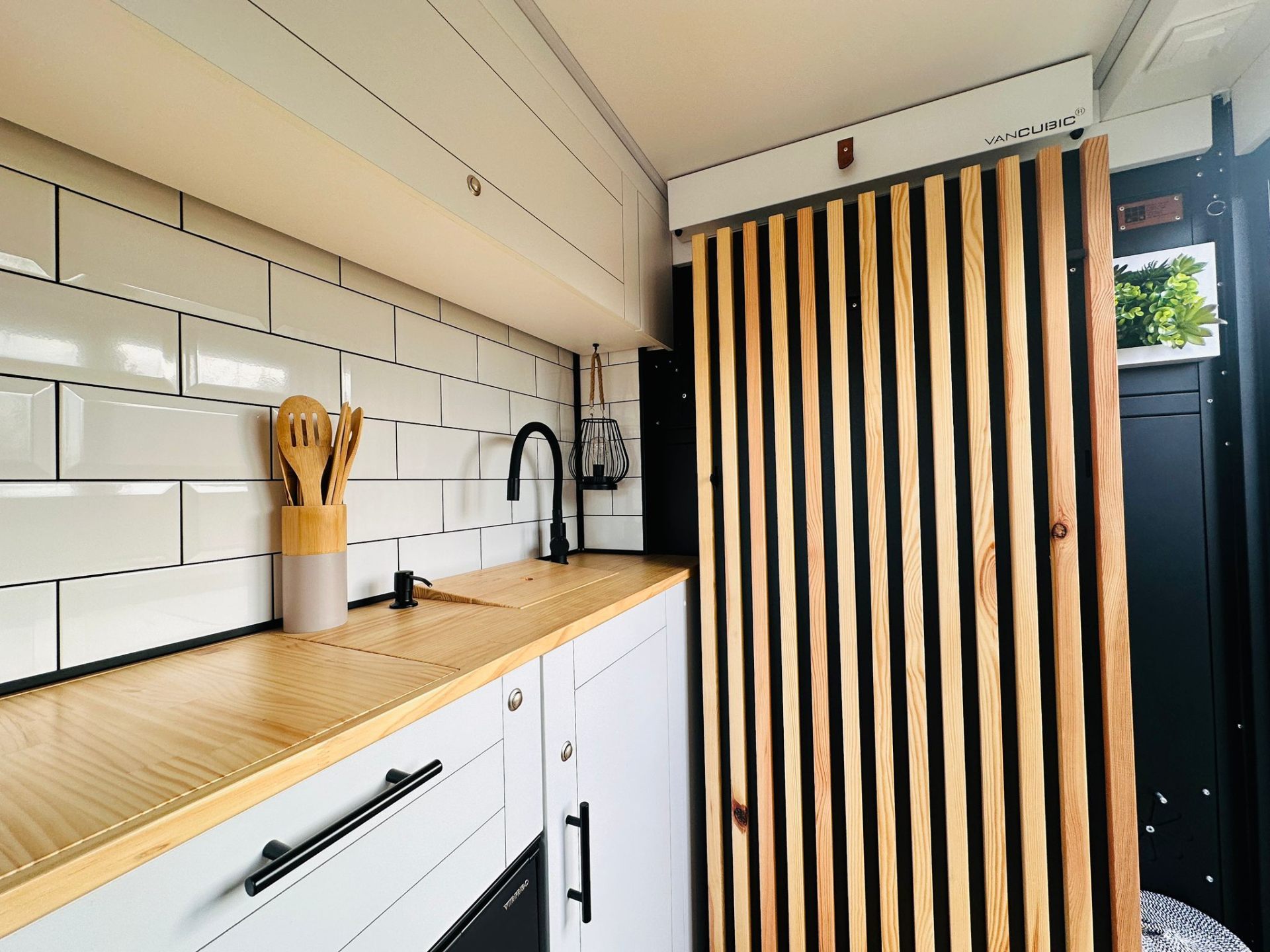 Camper van kitchen with wooden countertop and subway tiles